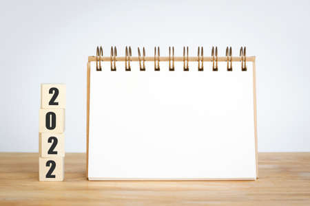 New year 2022 for new start with cubes wooden on table background, space for text on notepad mockup...