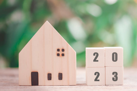 Wooden house model with wooden block number 2023 and copy space using as background concept to save...