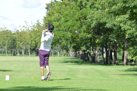 Golfers hit sweeping golf course in the summerの写真素材