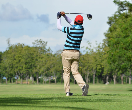 Golfers hit sweeping golf course in the summerの写真素材