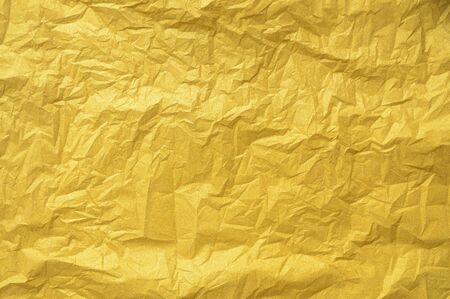 Crumped gold glittering foil leaf shiny wrapping paper glitter texture background for Christmas holiday seasonal wallpaper decoration and greeting card design elementの写真素材