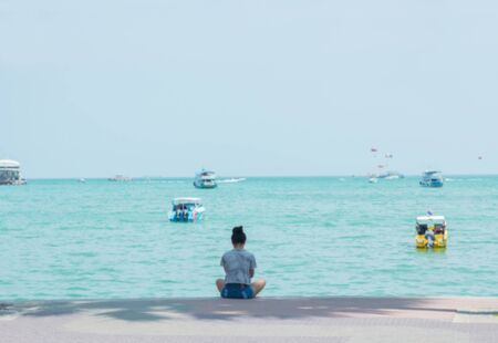 Blurry image of Teenage girl sitting next the sea looking alone.の写真素材
