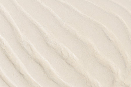 Beach sand background wave pattern, Fine sand closeup, Natural white brown sandy backdrop.の写真素材