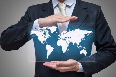 Businessman standing posture hand holding world map isolated on gray backgroundの写真素材