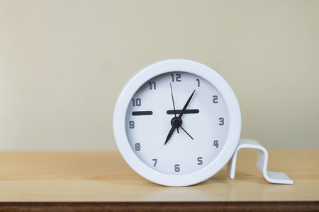 White clock on wooden table