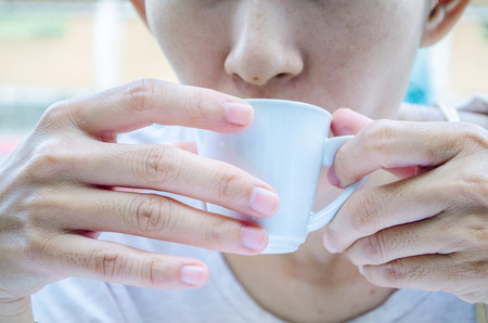 Asian women drinking tea from a white cup