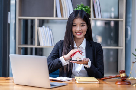 Smiling saleswoman real estate holding sample house, pretty sales presenting house modelの写真素材