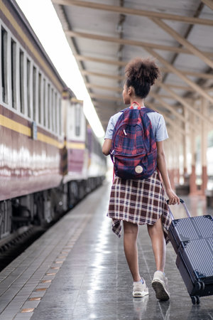 Young female traveler walking standing with a suitcase at train station. woman traveler tourist walking standing smiling with luggage at train stationの写真素材