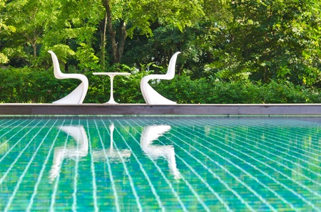 Two white deck chairs side swimming pool.の写真素材