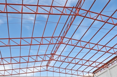Steel roof trusses sitting on concrete pole view from inside home factory. Blue sky with clouds in background.の写真素材