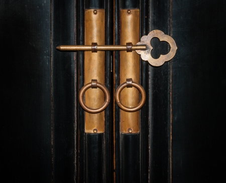 close up vintage copper key on the door of old black cabinet wood backgroundの写真素材