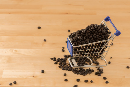 close up brown coffee beans in cart on pine wood board backgroundの写真素材