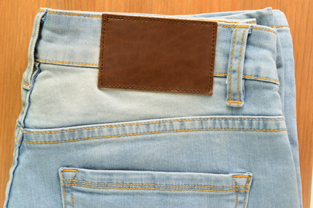 close up empty brown leather tag on white jeans on wood backgroundの写真素材