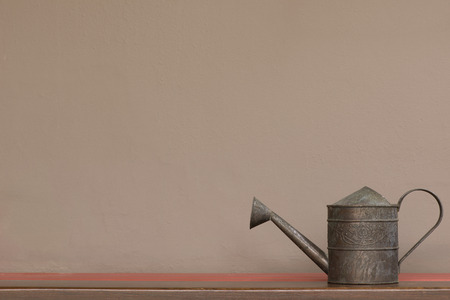 close up vintage style watering can on shelf with brown wall backgroundの写真素材