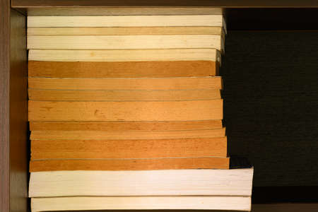 Old and well used hardback books or text books on a shelf  or library. Many Books Piles. Hardback books on wooden table top view. Back to school background with copy spaceの写真素材