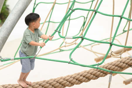 Funny kids, healthy teenager school boy enjoying activity in a climbing adventure park on a summer...