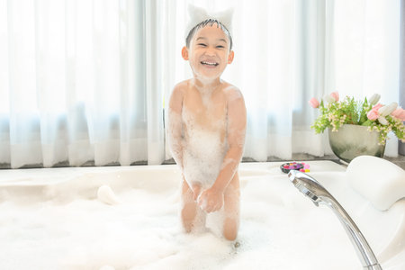 Portrait of smiling happy child asian boy is playing with white foam in tub bath at home.の写真素材