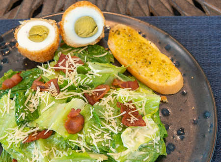 bacon salad with fried egg, lettuce, bread, cheese. Healthy and detox food concept. Ketogenic diet. Fresh vegetable salad plate on table backgroundの写真素材