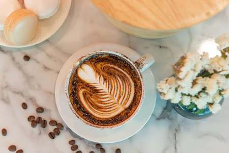 Close-up. Vintage tones Latte art coffee cup on glass table. Blurred leaf reflection background.の写真素材