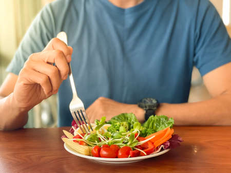 Man's hand scooping green salad. Healthy lifestyle and vegetarian vegan concept, Intermittent Fasting.の写真素材