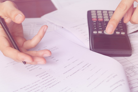 Business people counting on calculator sitting at the table. Close up of hands and stationery, soft...