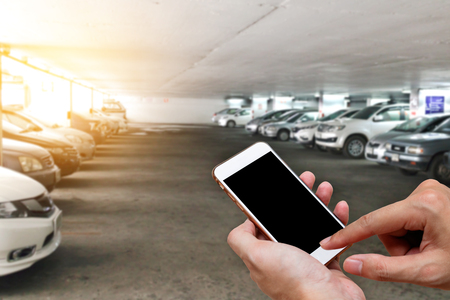 Smart phone showing blank screen in man hand with blur cars parkingの写真素材