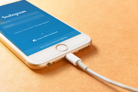 LAMPHUN, THAILAND - AUGUST 15, 2016: Screen shot Instagram application using Iphone6 charging with power bank on wood board. Instagram is largest and most popular photograph social networking.のeditorial素材