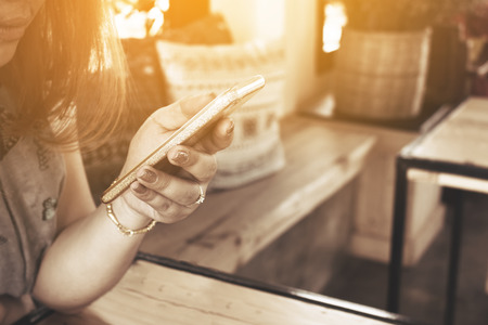 Close up woman hand typing message on smart phone in restaurant.の写真素材
