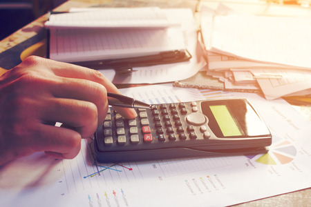 Close up man using calculator and doing finance in home office.