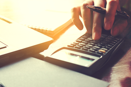 Closeup woman hand using calculator and calculate about cost at home office.の写真素材