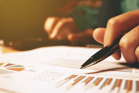 Close up of hand woman holding pen pointing on summary report chart and calculate finance.の写真素材