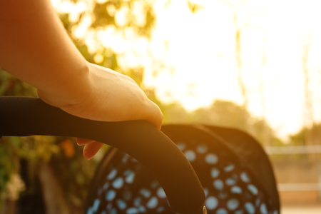 Close up mom pushing stroller in the park with sunset.の写真素材