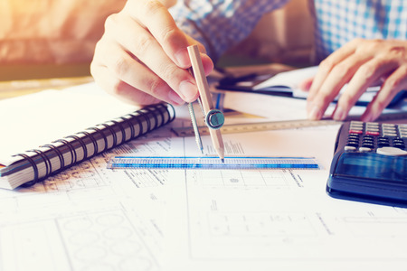 Architect man drawing geometric shape on blueprint at office table.