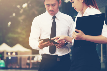 Two asian business standing with looking data result on tablet and estimate of budget finance.の写真素材