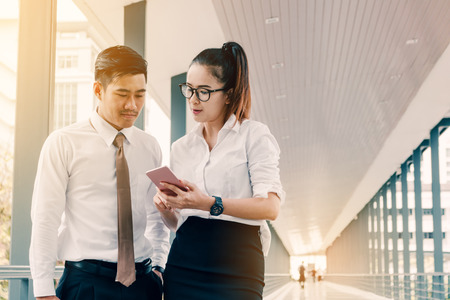 Business asian people talking about earnings results between the corridor of a company.の写真素材