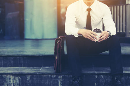 Businessman sitting in front of company building with hope concept.の写真素材