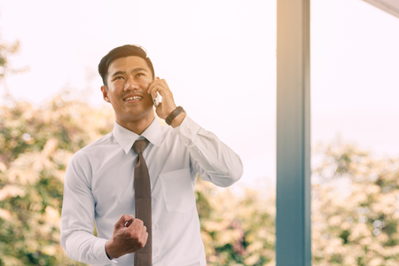 Young asian handsome businessman talking on phone and happiness for work.の写真素材