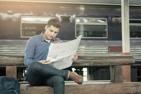 Traveler man sitting at train station and looking on map for travel planning.の写真素材