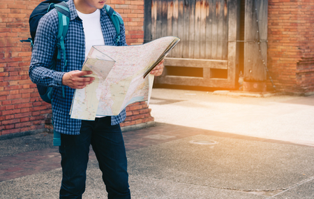 Handsome man holding map paper with finding location for travel.の写真素材