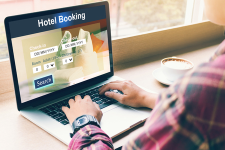 Man using laptop to make hotel booking reservation in cafe restaurant.の写真素材