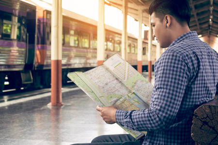 Traveler man sitting at train station and looking on map for travel planning.の写真素材