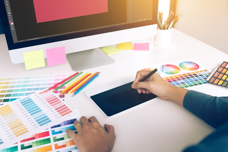 Freelance creative designers working on desk using digital graphic tablet and drawing with pen in modern home office.の写真素材