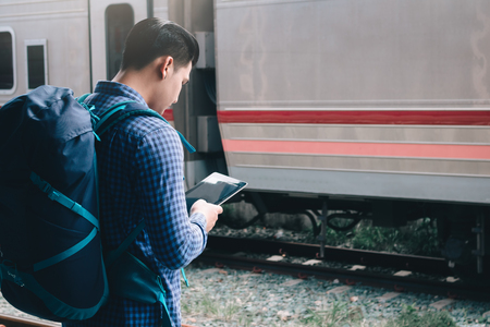 Smart young asian man using tablet at train station.の写真素材