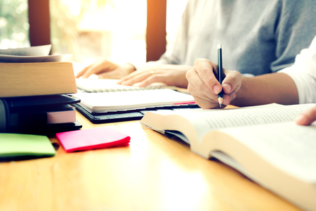 Teenage student works on homework in his room and writing in notebook.の写真素材