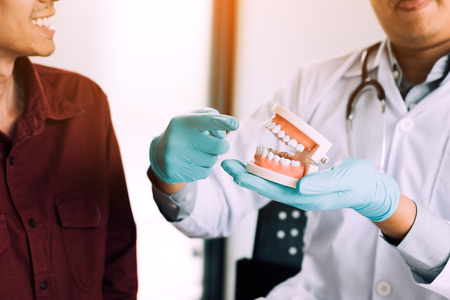 Dentists are demonstrating how to brush their teeth correctly to patient in clinic room.