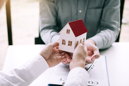 Home agents are giving house gifts to new home buyers in office room.の写真素材