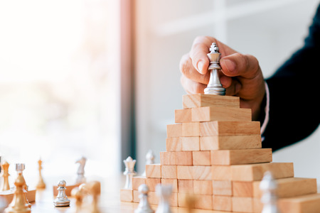 Businessman hand picking chess on top block wood about leadership concept.の写真素材