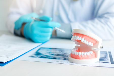 Close up dentures with dentist working on table in clinic.