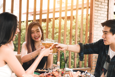 Teeneger asian friends clinking glasses while enjoying an evening meal in a restaurant.の写真素材
