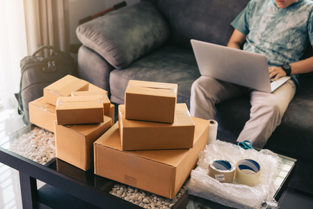Asian teenager working in home office going over inventory and shipping on desk.の写真素材